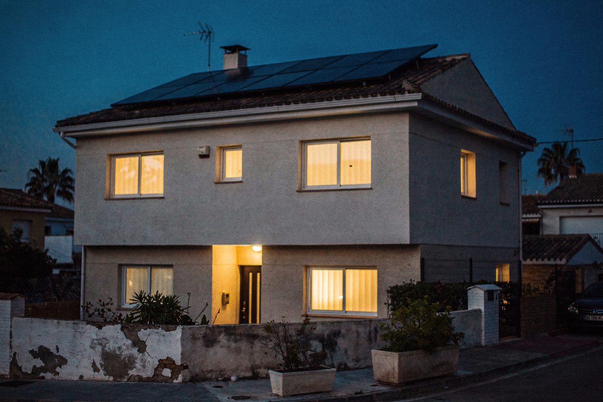 Vivienda al anochecer con la silueta de los paneles solares en el tejado